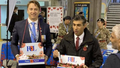Rishi Sunak talks to commuters while selling poppies at the exit of Westminster Tube station.