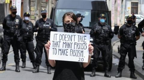 A protester in front of police in Sarajevo holds a placard that reads: "It doesn't take that many fascists to make fascism". Photo: 16 May 2020
