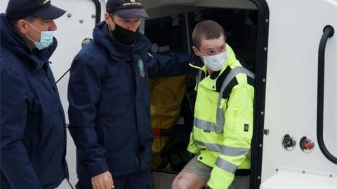 A Belarusian survivor disembarks from a Greek coast guard vessel at the port of Corfu after being rescued from the burning Italian-flagged Euroferry Olympia, which sailed from Greece to Italy, on the island of Corfu, Greece, February 20, 202