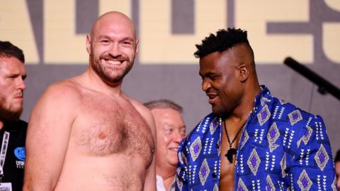 Tyson Fury grins as Francis Ngannou looks at him