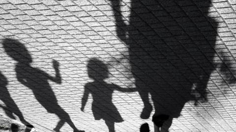 Blurry shadow of a little boy and a girl walking with adults in black and white