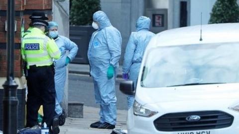 Forensics staff and police officers stand at the scene near Great Scotland Yard
