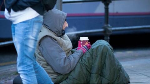 Homeless man with a hot drink in the cold weather