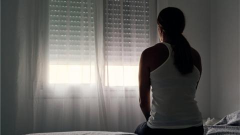 Woman sitting on bed near window