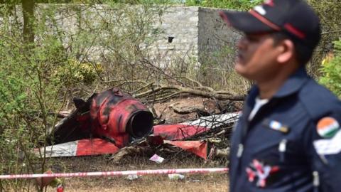 An Indian Air Force personnel walks past the wreckage of an aircraft