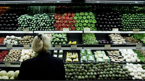 A woman looking at fruit and vegetables in a supermarket