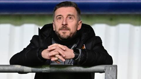 Northampton Town boss Jon Brady watching from the TV gantry against Oxford United