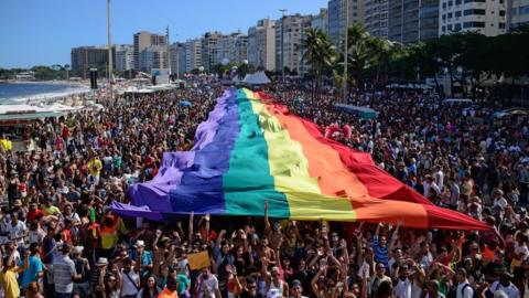 Revellers march with a giant rainbow flag during the annual Gay Pride Parade at Copacabana beach in Rio de Janeiro, Brazil