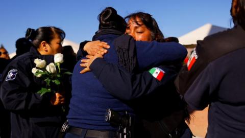 People embrace as they pay homage to the prison guards killed during a riot at a prison in Ciudad Juárez, Mexico