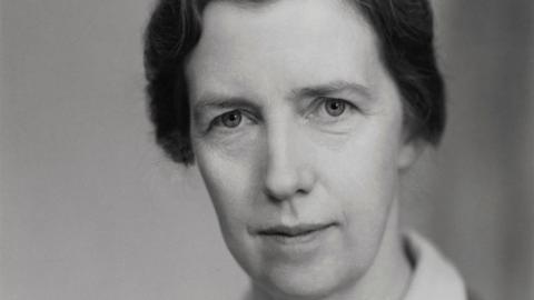 Dame Mary Cartwright is seen looking at the camera in a black and white photo. It is a close-up of her face and she has dark hair that is tied back.