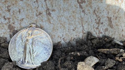 World War One medal on soil in front of spade