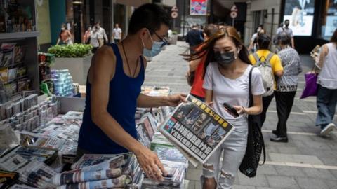 A woman buys a copy of Apple Daily newspaper at a news stand in Hong Kong, China, 18 June 2021.
