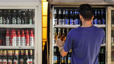 A shopworker arranges beer bottles in a refrigerator at a liquor shop in the Bataween district in the centre of Iraq's capital Baghdad on 5 December 2020