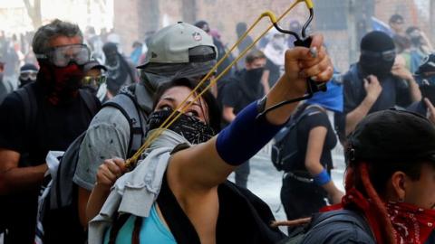A woman holds a slingshot during a protest