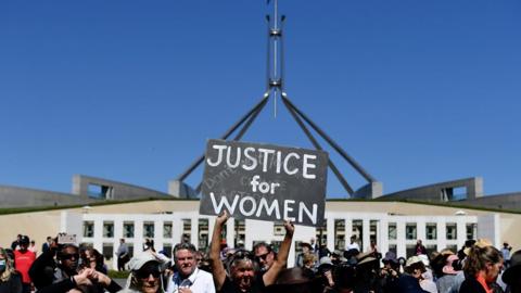 Woman holding sign in front of parliament house