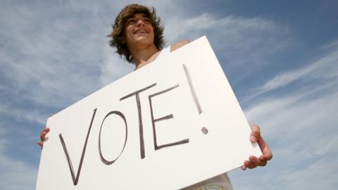 Young person holding a voting card