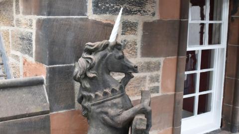 A carved stone unicorn with a white painted horn, viewed side on
