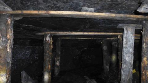 A photo from inside the mine showing "pallet" wood holding up the ceiling