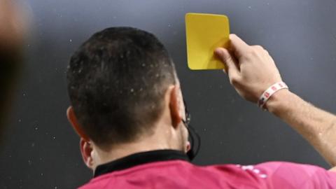 Referee showing yellow card