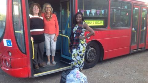 Landlady Eunice and two members of the fundraising committee stand with the bus