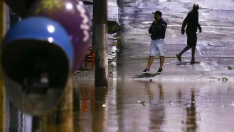 People stand in a flooded street after heavy rain in Caieiras, Brazil, 30 January 2022