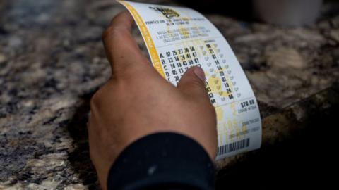 A customer holds the lottery ticket he bought at a gas station in Austin, Texas
