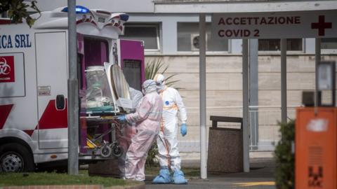 Medical staff collect a patient from an ambulance in Italy