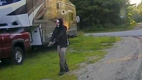 A picture released by Maine State Police shows a man strolling down a street in Hollis, Maine, wearing a clown mask and with a machete taped to his amputated arm