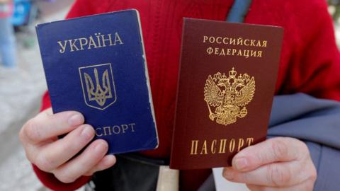 A woman poses with her Ukrainian passport (blue) and new Russian passport (red) in Simferopol, Crimea, 7 April 2014