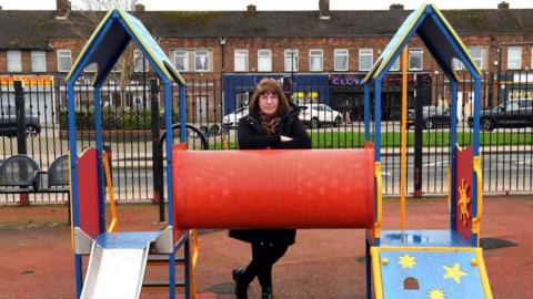 A councillor standing with play equipment