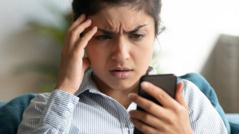 A young woman concerned by something on her phone