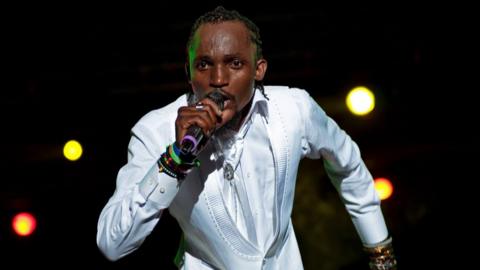 Mowzey Radio performing in a white suit