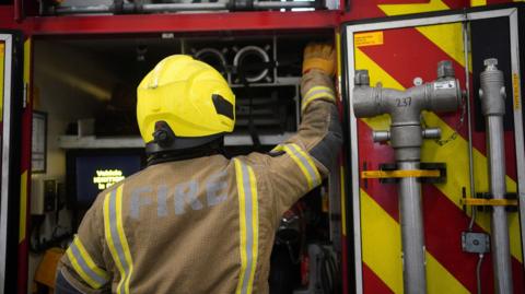 Firefighter reaches into fire engine
