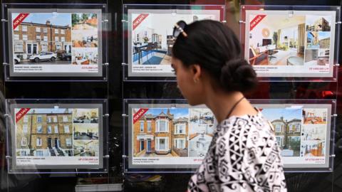 A woman looks over properties at an estate agents in London