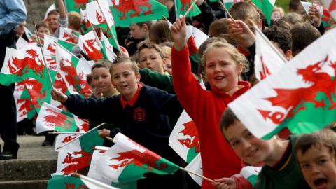 Children wave flags during a visit by HM Queen Elizabeth II and Prince Philip, Duke of Edinburgh to Caernarfon Castle on April 27, 2010