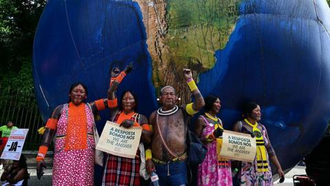 Indigenous people pose next to a giant inflatable globe during the "Indigenous People Global March" at the COP30 UN Climate Change Conference in Belem, Para state, Brazil, on November 17, 2025.