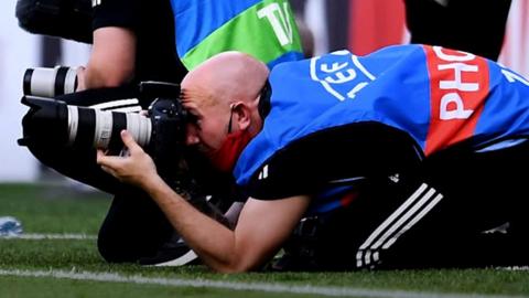 Elis James and John Robins speak to John Smith about his role as official photographer for the Wales team and how he deals with 'Welshman's thigh'.