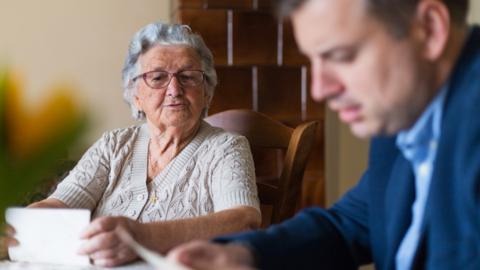 An elderly woman sits with a man