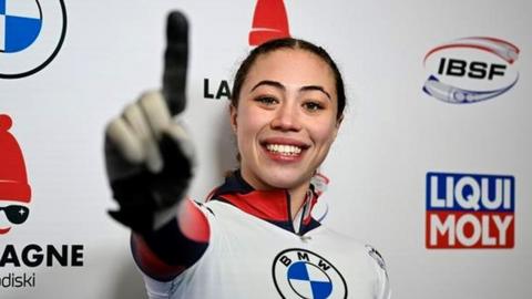 Tabby Stoecker holds her right index finger to the camera in celebration after winning the Skeleton World Cup gold medal