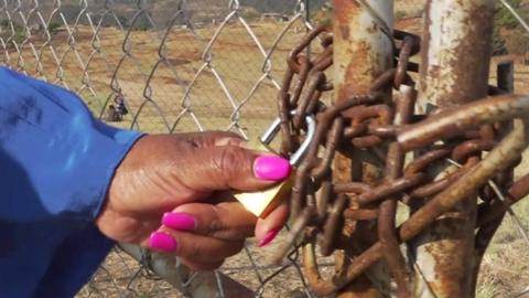 A woman's hand holding on a padlock chaining a clinic in Lesotho