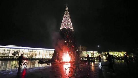 Image shows protesters setting fire to Christmas tree