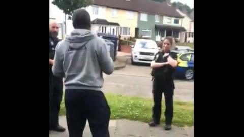 Two white police officers speaking to a black man