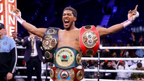 Anthony Joshua celebrates a win with all his belts