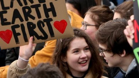 a young woman holds up a sign reading "Planet Earth First" at a demonstration against climate change in Hamburg