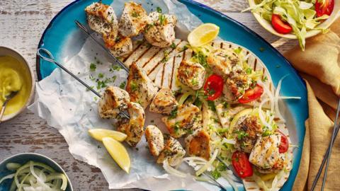 Chicken souvlaki served with wraps and shredded salad on a blue plate