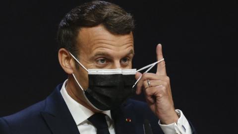 France's President Emmanuel Macron takes off his facemask before giving a press conference during the European Social Summit hosted by the Portuguese presidency of the Council of the European Union at the Palacio de Cristal in Porto on May 8, 2021