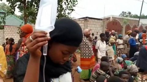 A woman holds up an intravenous drip