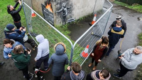 Visitors take pictures of the new Banksy piece in Port Talbot