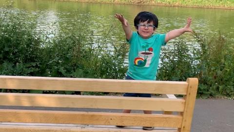 A child waving from a bench