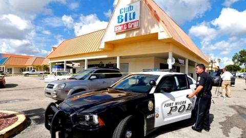 A Fort Myers police officer is seen at a parking lot of Club Blu after a shooting in Fort Myers